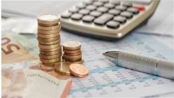 Rekenmachine met een stapeltje los geld, briefgeld en een pen